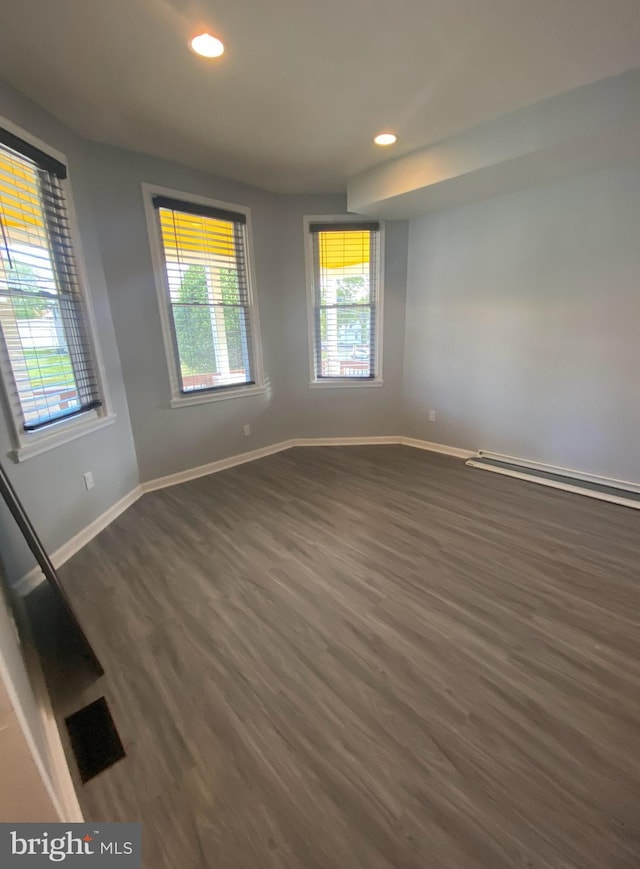 spare room with dark hardwood / wood-style flooring and baseboard heating