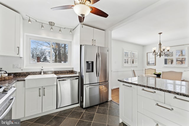 kitchen with appliances with stainless steel finishes, dark stone counters, pendant lighting, sink, and white cabinetry