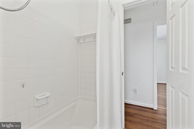 bathroom with hardwood / wood-style flooring and shower / bath combo