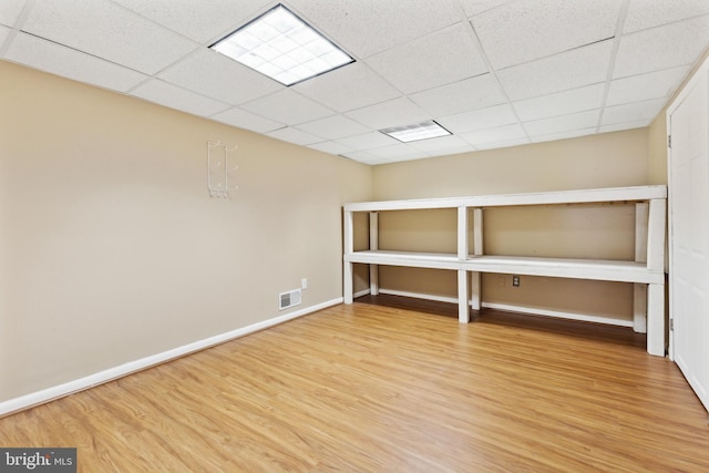 basement featuring a paneled ceiling and hardwood / wood-style floors