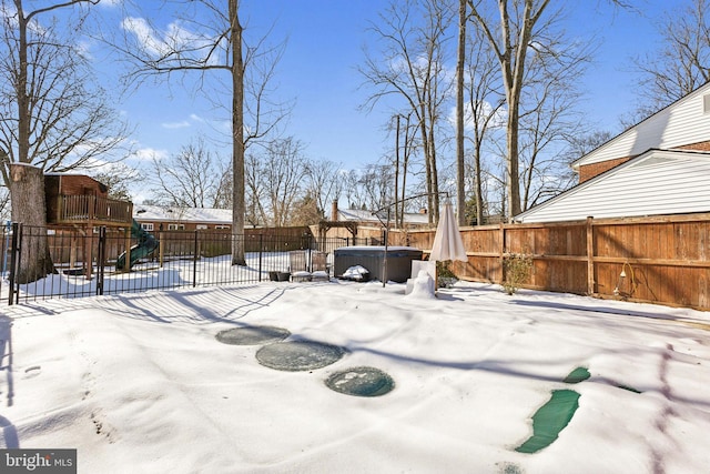 yard covered in snow featuring a playground and a hot tub