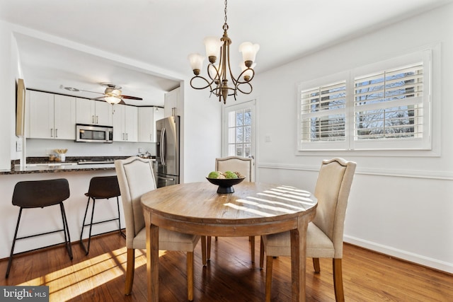 dining area featuring ceiling fan with notable chandelier and wood-type flooring