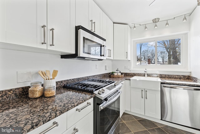 kitchen with sink, dark stone counters, appliances with stainless steel finishes, and white cabinetry