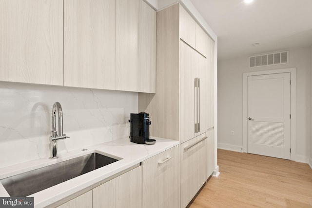 kitchen with sink, light hardwood / wood-style flooring, light brown cabinetry, and decorative backsplash