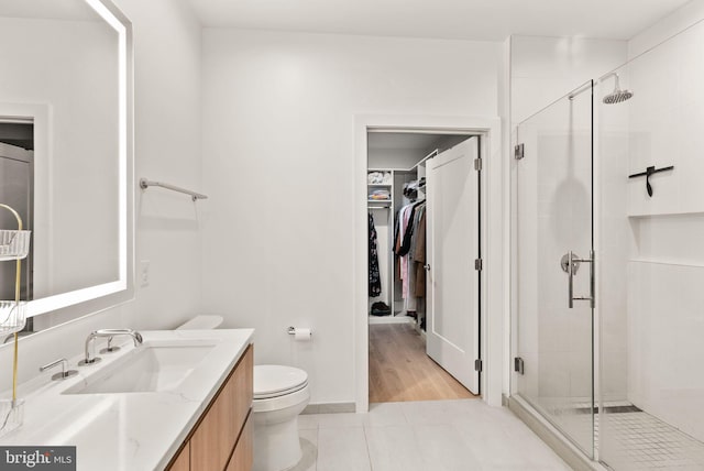 bathroom featuring toilet, an enclosed shower, vanity, and tile patterned floors