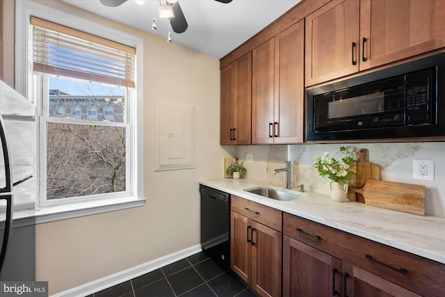 kitchen featuring sink, light stone counters, dark tile patterned floors, backsplash, and black appliances