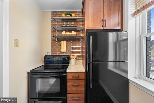 kitchen with black electric range oven, light stone counters, and refrigerator