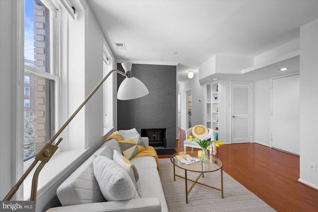 living room with hardwood / wood-style floors, plenty of natural light, and a brick fireplace