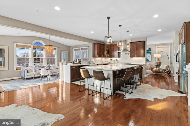 kitchen with hanging light fixtures, lofted ceiling, a center island, and wall chimney exhaust hood