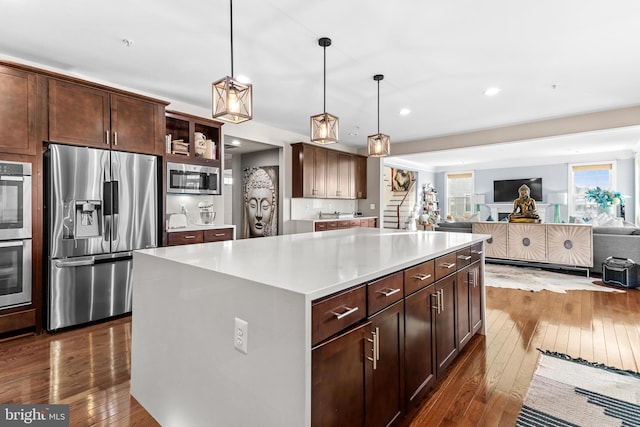 kitchen with dark hardwood / wood-style flooring, decorative light fixtures, stainless steel appliances, and a center island