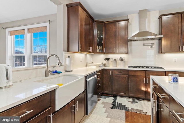 kitchen with wall chimney range hood, sink, dark brown cabinets, black gas cooktop, and stainless steel dishwasher