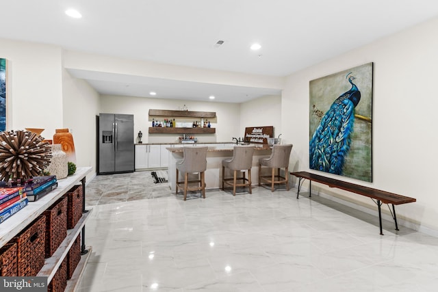 bar featuring white cabinetry and stainless steel fridge