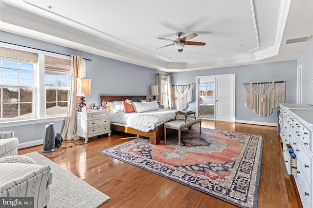 bedroom featuring crown molding, a tray ceiling, ceiling fan, and hardwood / wood-style flooring