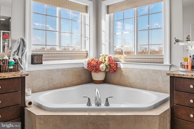 bathroom with vanity and tiled bath