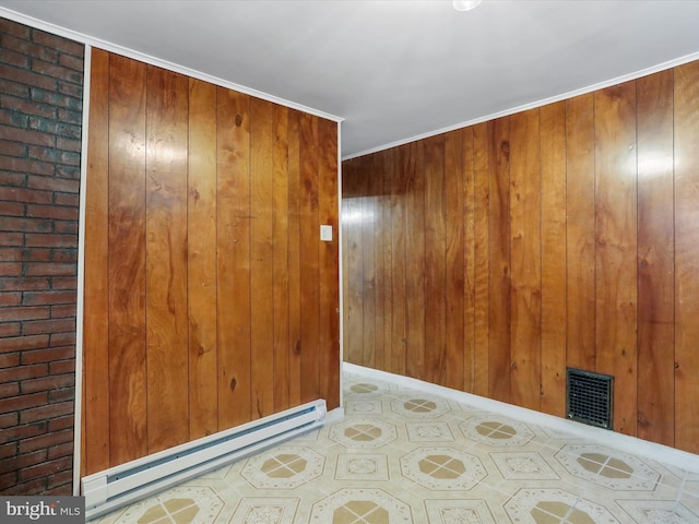 spare room featuring ornamental molding, baseboard heating, and wooden walls