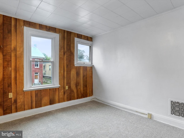 carpeted spare room featuring wood walls