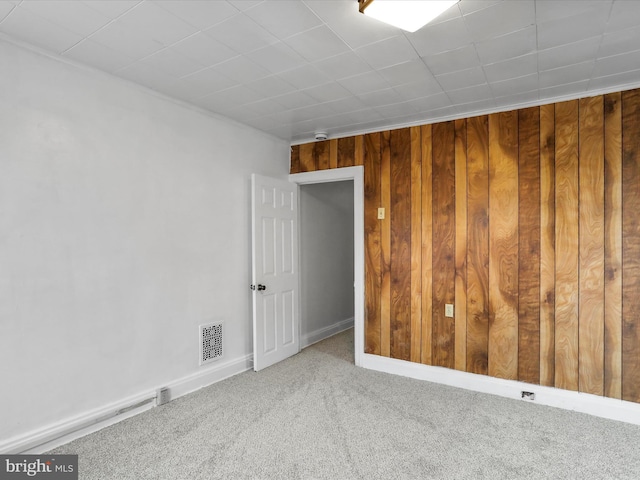 empty room with carpet and wood walls