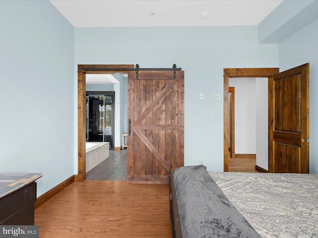 bedroom with hardwood / wood-style floors and a barn door