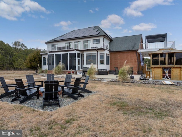 back of property with a patio area, a sunroom, a balcony, and an outdoor fire pit