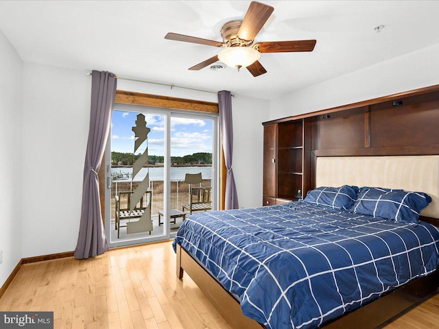 bedroom featuring ceiling fan, a water view, wood-type flooring, and access to outside