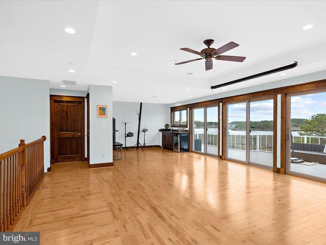 interior space featuring ceiling fan, light hardwood / wood-style floors, and a water view