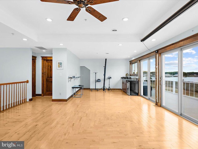 workout room with ceiling fan and a water view