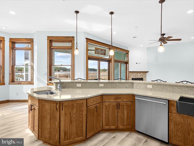 kitchen with light stone countertops, stainless steel dishwasher, ceiling fan, sink, and light hardwood / wood-style floors