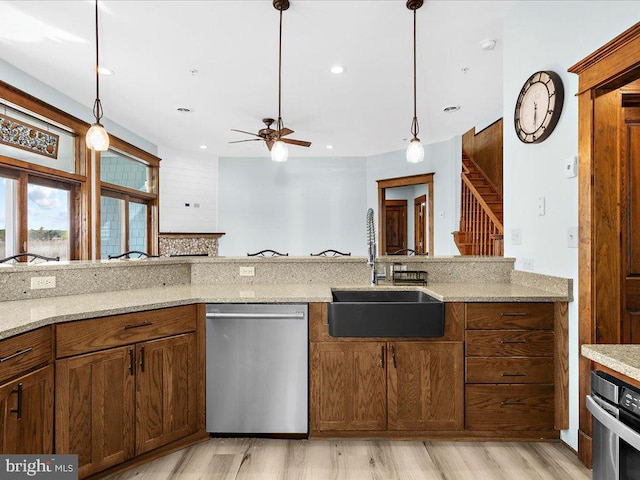 kitchen with light stone counters, sink, stainless steel appliances, and decorative light fixtures