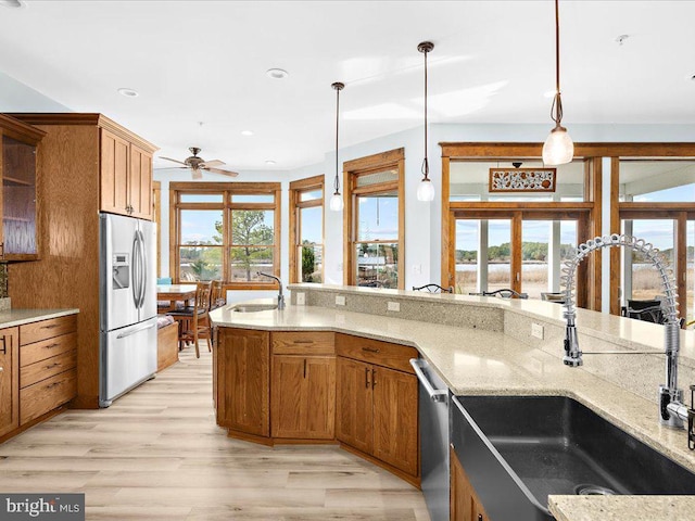 kitchen featuring ceiling fan, sink, light hardwood / wood-style flooring, pendant lighting, and appliances with stainless steel finishes