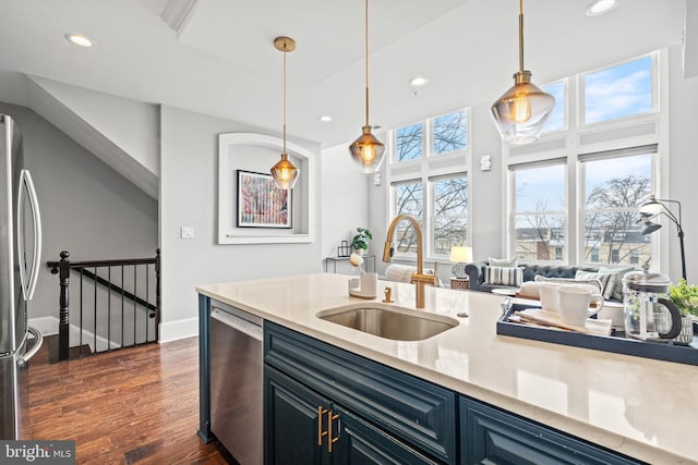 kitchen with sink, dark wood-type flooring, stainless steel appliances, blue cabinets, and decorative light fixtures