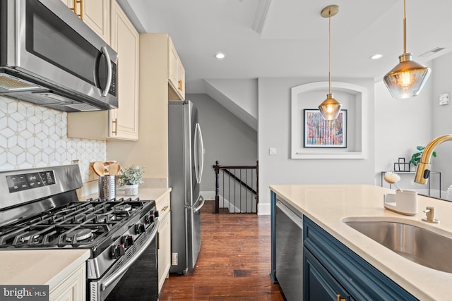 kitchen featuring backsplash, stainless steel appliances, blue cabinets, sink, and hanging light fixtures