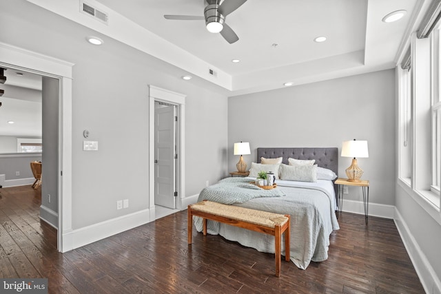 bedroom with multiple windows, a tray ceiling, ceiling fan, and dark hardwood / wood-style floors