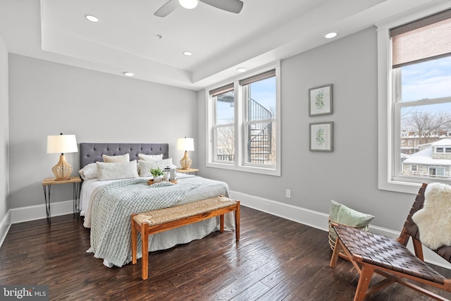 bedroom featuring dark hardwood / wood-style flooring, a tray ceiling, and ceiling fan