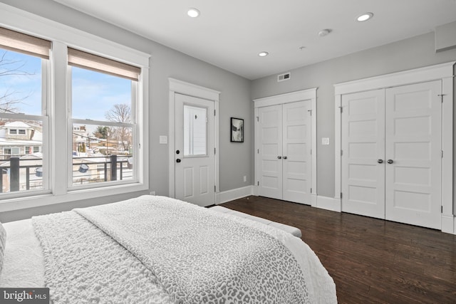 bedroom featuring two closets and dark hardwood / wood-style floors