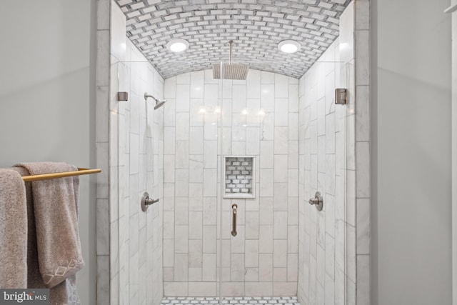 bathroom featuring a shower with shower door, brick ceiling, and vaulted ceiling