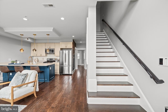 kitchen featuring a kitchen breakfast bar, tasteful backsplash, stainless steel appliances, a kitchen island with sink, and pendant lighting