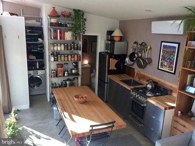 kitchen featuring sink, stainless steel appliances, washer / clothes dryer, and a wall mounted AC