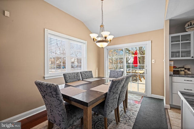 dining area featuring vaulted ceiling and an inviting chandelier