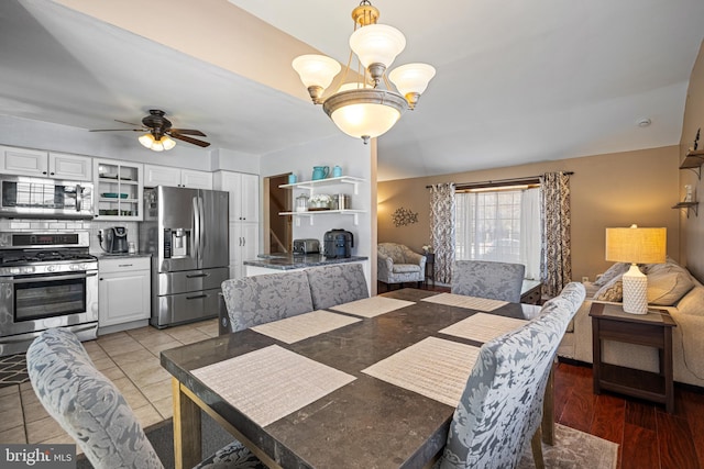 tiled dining room featuring ceiling fan with notable chandelier