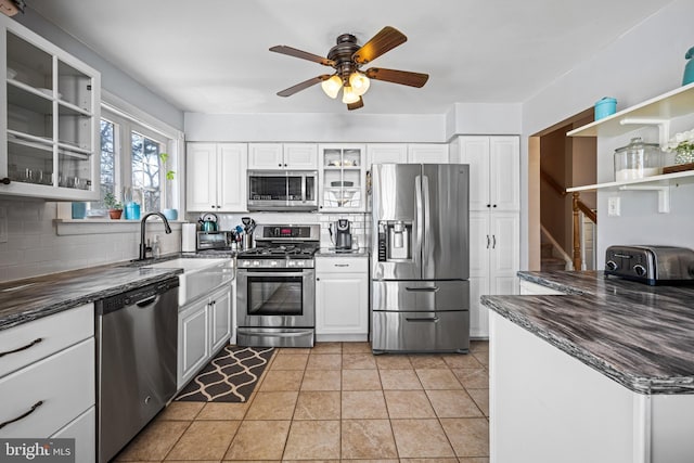 kitchen featuring appliances with stainless steel finishes, sink, white cabinets, decorative backsplash, and light tile patterned floors