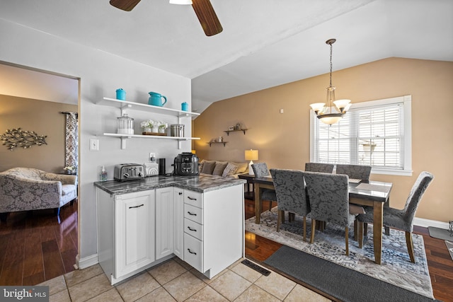 kitchen with pendant lighting, light tile patterned floors, ceiling fan, white cabinets, and vaulted ceiling