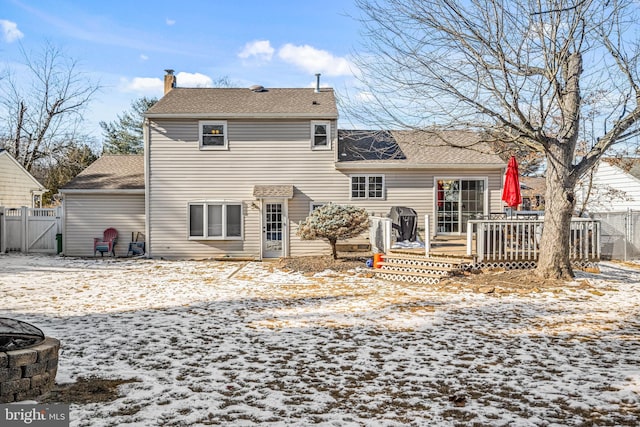 snow covered rear of property featuring an outdoor fire pit and a deck