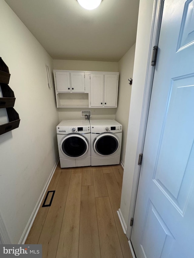 laundry area with cabinets, washer and dryer, and light wood-type flooring