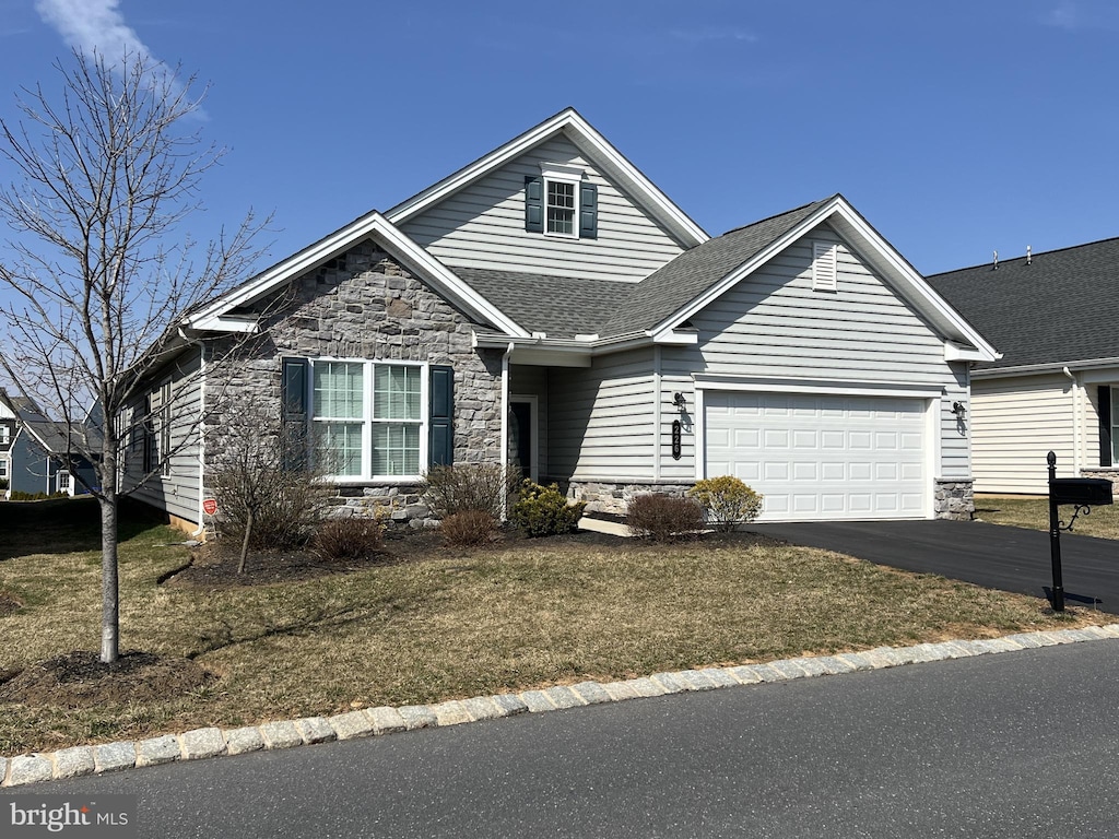 view of front of home featuring stone siding, driveway, a shingled roof, and a garage