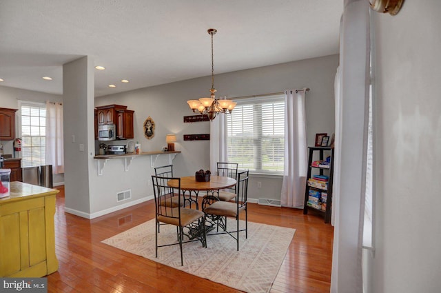 dining room with light hardwood / wood-style floors and an inviting chandelier