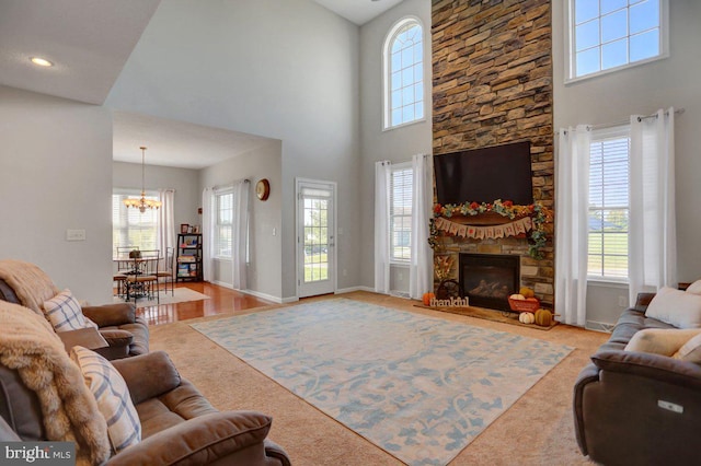 carpeted living room with a notable chandelier, a wealth of natural light, a fireplace, and a high ceiling