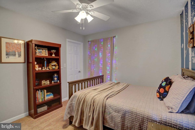 bedroom with ceiling fan, light colored carpet, and a textured ceiling