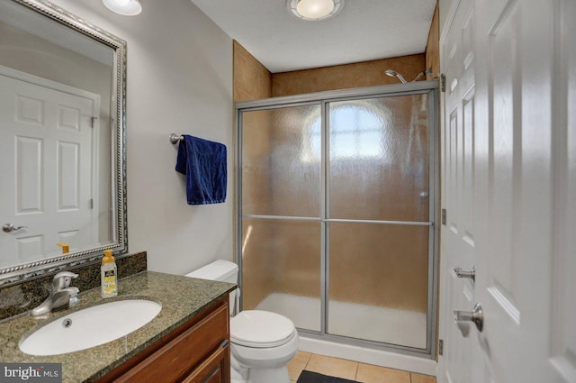 bathroom with tile patterned flooring, vanity, an enclosed shower, and toilet