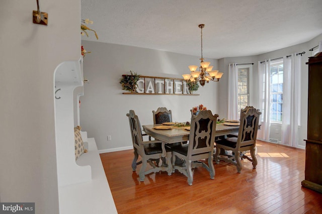 dining space with hardwood / wood-style flooring, a notable chandelier, and a textured ceiling