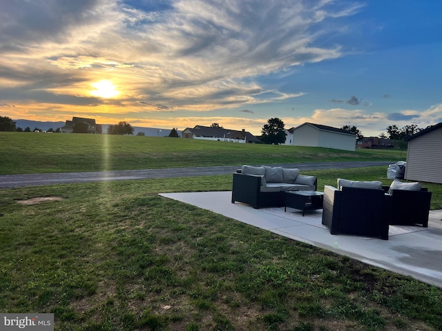 yard at dusk with an outdoor living space and a patio area